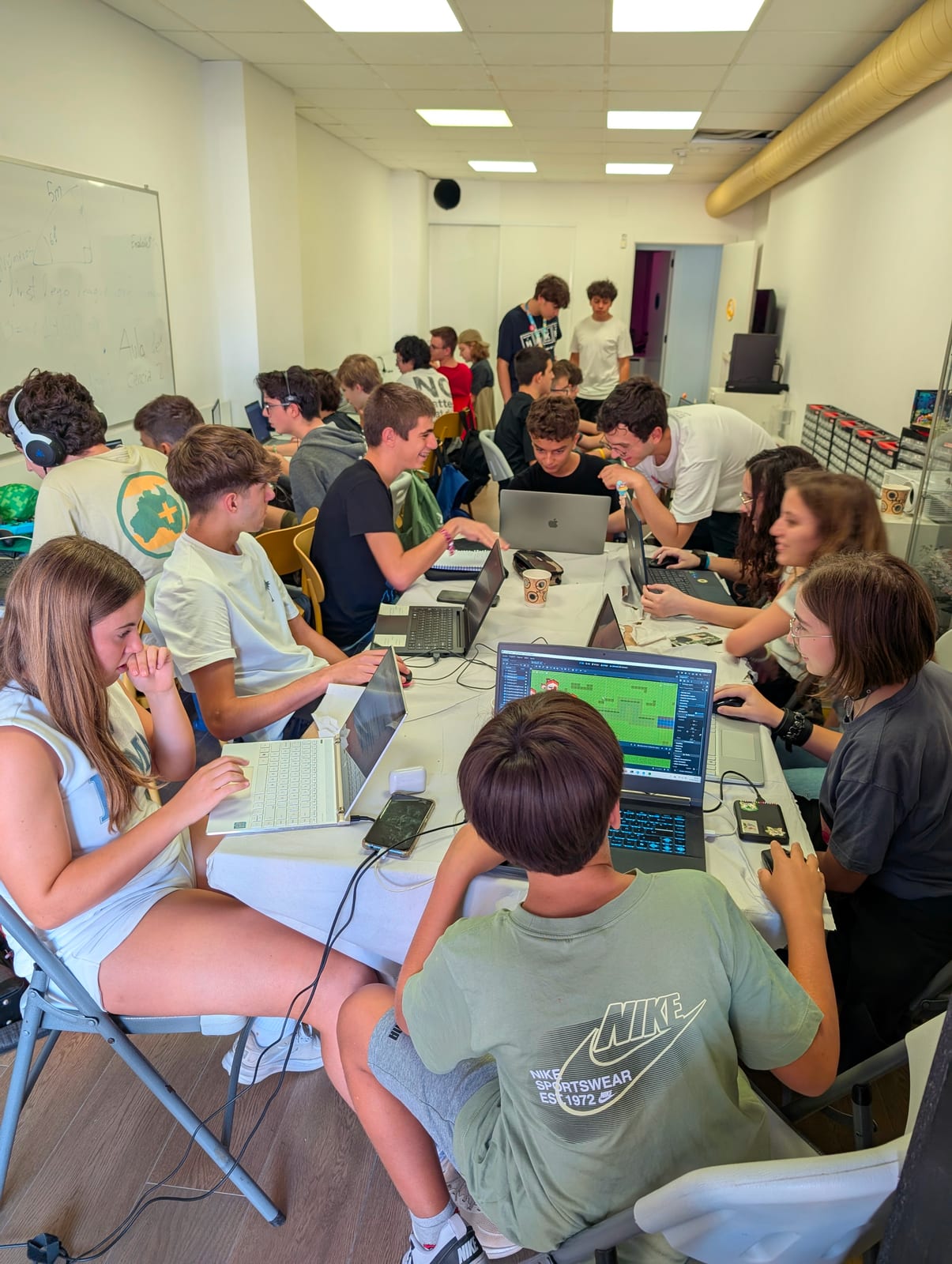 Teens work with their laptops at Daydream Valencia, and Daniel Negre helps one of them.